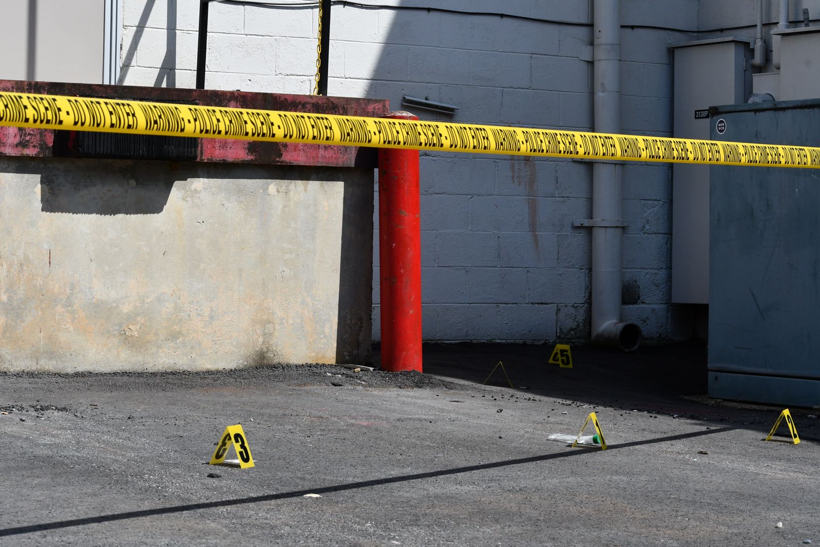 Numbered evidence markers and police tape at an outdoor shooting scene